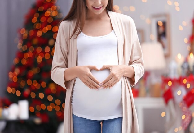 Glückliche schwangere frau im weihnachtlich dekorierten zimmer