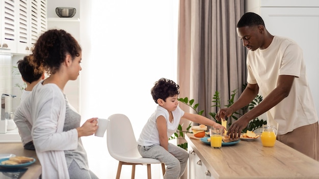 Glückliche schwarze Familie, die den Tisch für das Essen deckt