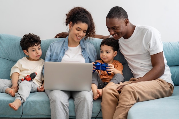 Glückliche schwarze Familie, die etwas auf Laptop beobachtet und lacht