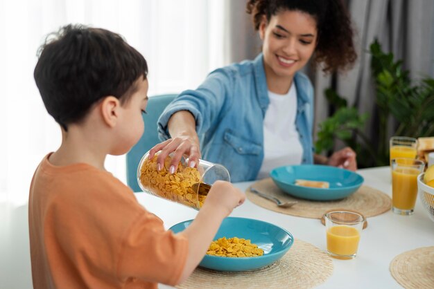 Glückliche schwarze Familie mit Mutter, die Kind mit Cornflakes dient