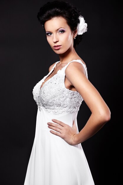 Glückliche sexy schöne Braut Brunettefrau im weißen Hochzeitskleid mit Frisur und hellem Make-up