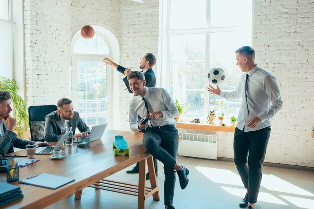 Glückliche sorglose Kollegen, die Spaß im Büro haben, während ihre Mitarbeiter hart und hoch konzentriert arbeiten.