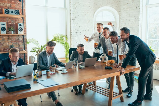 Glückliche sorglose Kollegen, die Spaß im Büro haben, während ihre Mitarbeiter hart und hoch konzentriert arbeiten.