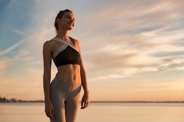 Glückliche Sportfrau am Strand, der beiseite schaut.