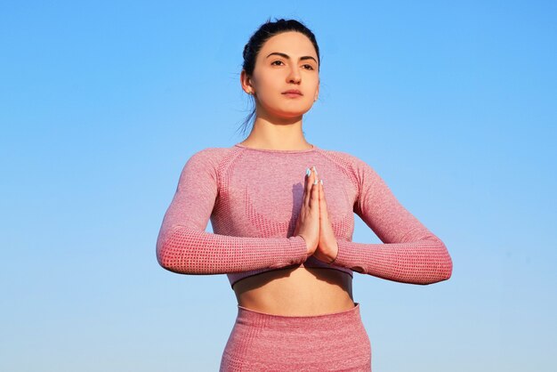 Glückliche sportliche Frau, die Yoga im Freien praktiziert