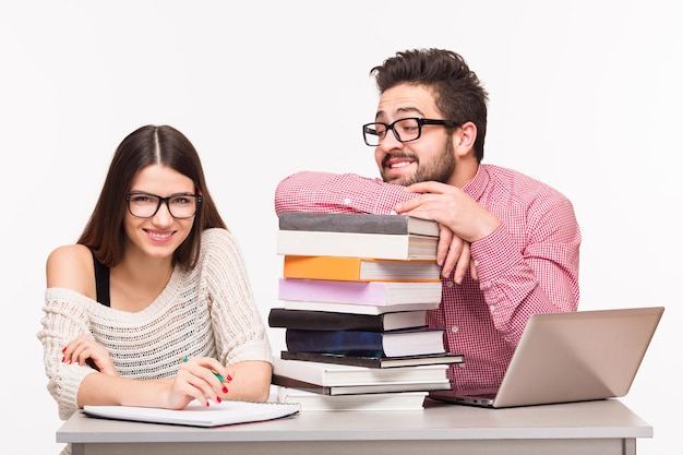 Glückliche Studenten, die am Tisch sitzen und sich auf Prüfungen vorbereiten. Glückliche Dame, die in die Kamera schaut, und ihr Gruppenkamerad, der sie ansieht.