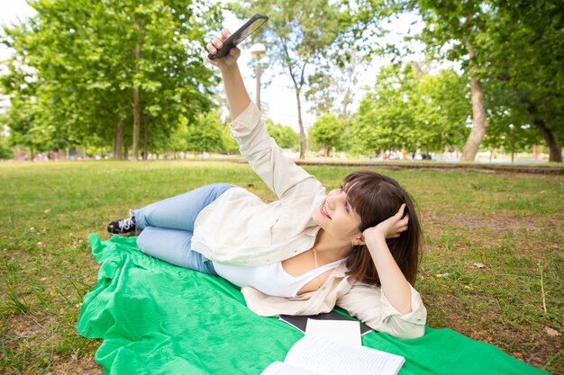 Glückliche Studentin, die selfie im Park nimmt