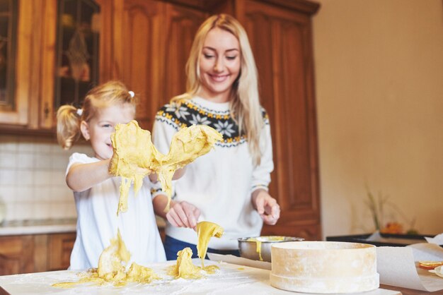 Glückliche Tochter und Mutter in der Küche backen Kekse