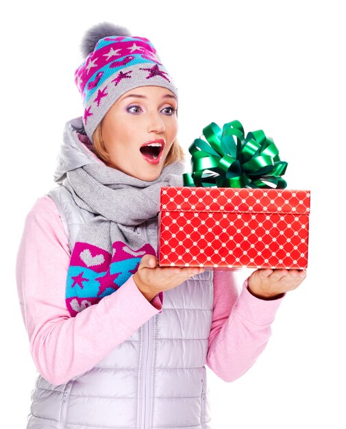 glückliche überraschte Frau mit einem Weihnachtsgeschenk in einer Winteroberbekleidung lokalisiert auf Weiß