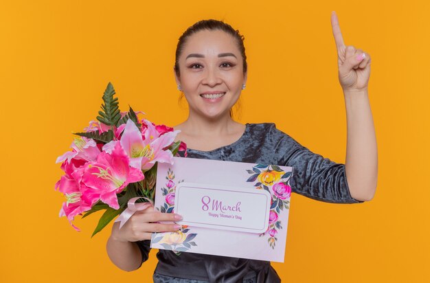 glückliche und positive asiatische Frauenmutter, die Blumenstrauß und Grußkarte hält, die internationalen Frauentagsmarsch feiert