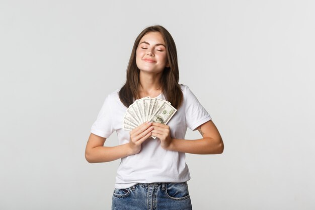 Glückliche und zufriedene lächelnde Frau schließen Augen und genießen, Geld zu haben.