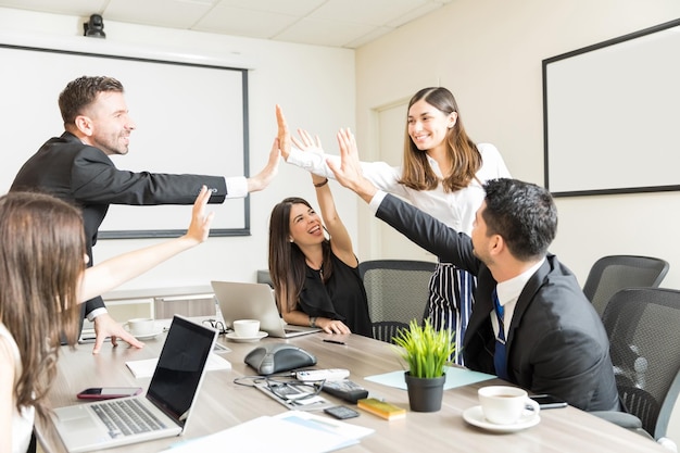 Glückliche Untergebene geben High-Five, nachdem sie ein neues Projekt im Sitzungssaal erfolgreich durchgeführt haben