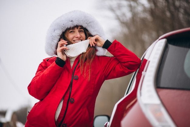 Kostenloses Foto glückliche unterhaltung der frau am telefon draußen mit dem auto im winter