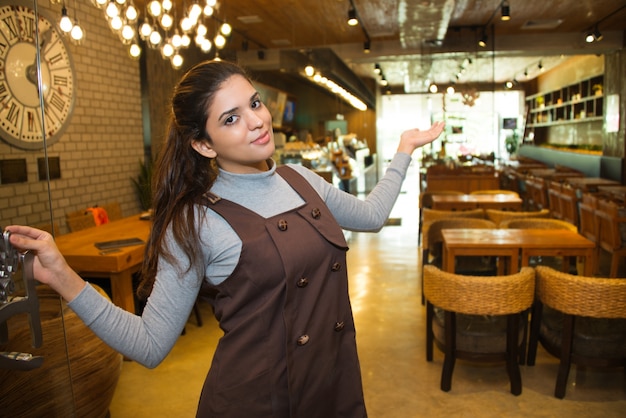 Glückliche weibliche kleine Unternehmer zeigt ihr Café
