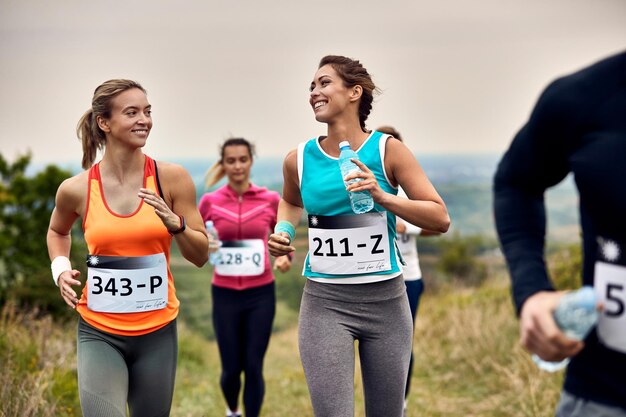 Glückliche weibliche Läufer sprechen beim Marathonspielen in der Natur