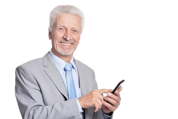 Glücklicher älterer geschäftsmann, der mit smartphone auf weißem hintergrund aufwirft