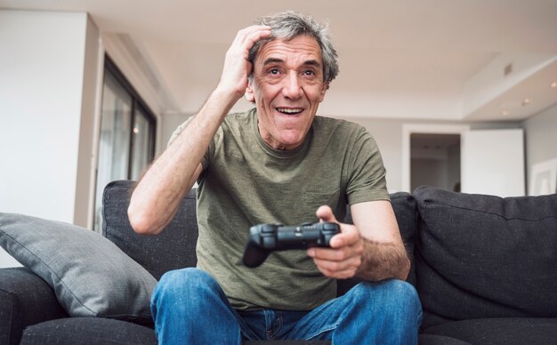 Glücklicher älterer Mann, der zu Hause Videospiel spielt