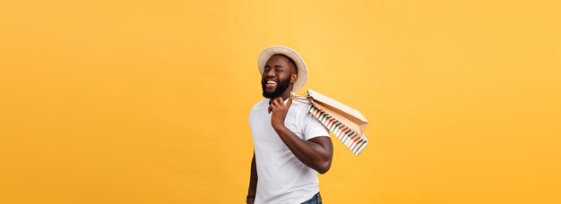 Glücklicher afrikanisch-amerikanischer Mann, der Einkaufstaschen auf gelbem Hintergrund hält, urlaubt Konzept