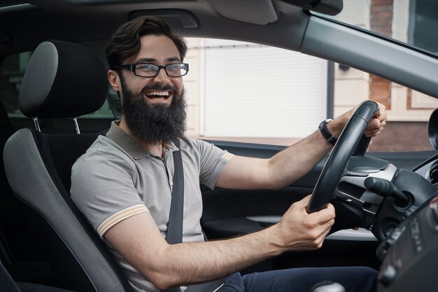 Glücklicher charismatischer Mann, der ein Auto fährt