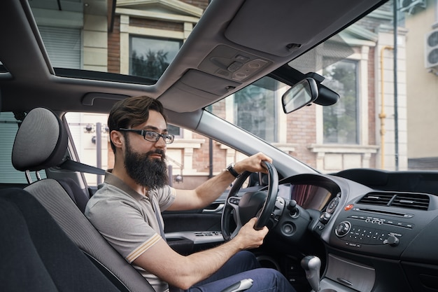 Glücklicher charismatischer Mann, der ein Auto fährt