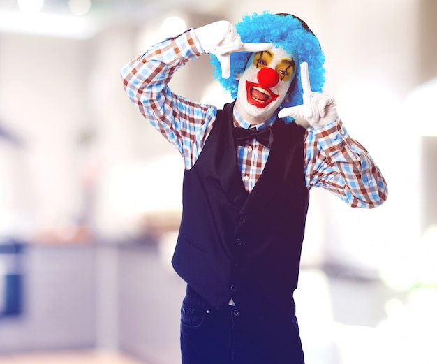Kostenloses Foto glücklicher clown einen rahmen mit seinen händen