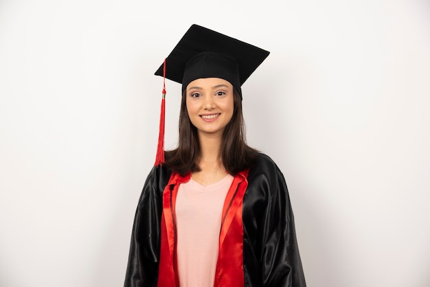 Glücklicher Doktorand im Kleid, das auf weißem Hintergrund steht.