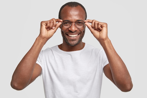 Glücklicher dunkelhäutiger Lehrer trägt eine große Brille und lächelt positiv