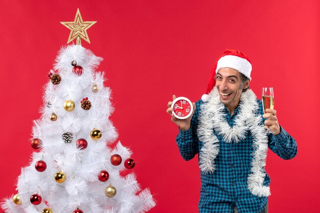 Glücklicher emotionaler junger Mann mit Weihnachtsmannhut und einem Glas Wein und Halten