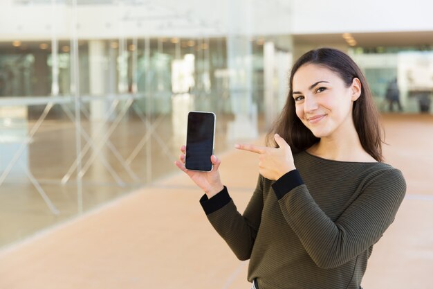 Glücklicher erfüllter Mobiltelefonbenutzer, der auf leeren Bildschirm zeigt