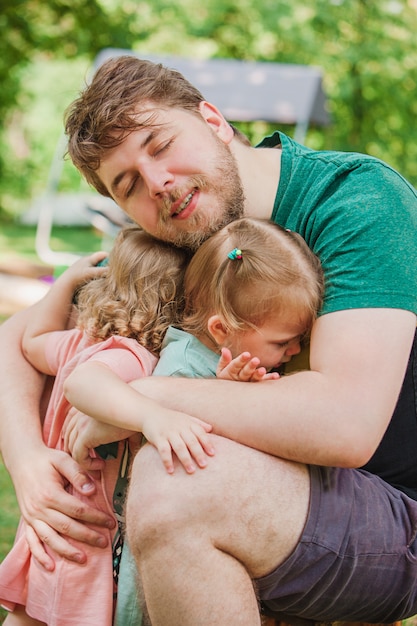 Glücklicher Familien- und Vatertag. Kindertöchter umarmen Papa