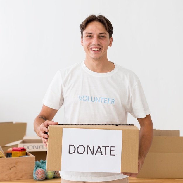 Glücklicher Freiwilliger, der eine Spendenbox hält