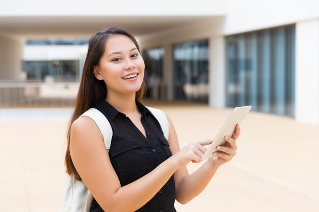 Glücklicher freundlicher Student, der Tablette verwendet