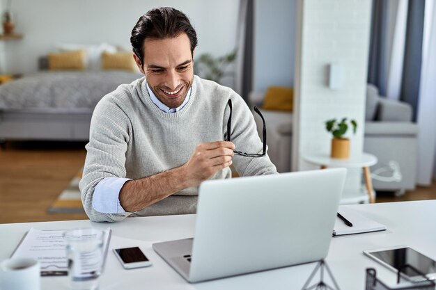 Glücklicher Geschäftsmann, der Computer verwendet, während er zu Hause arbeitet