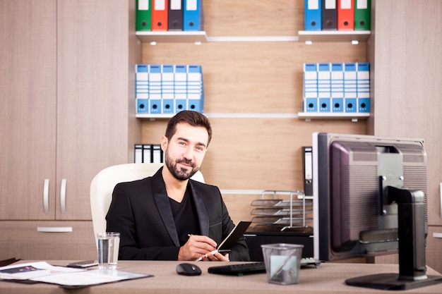 Glücklicher Geschäftsmann, der in seinem Büro arbeitet. Kaufmann im beruflichen Umfeld