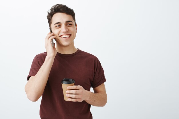 glücklicher gutaussehender Mann im roten T-Shirt, der per Telefon spricht