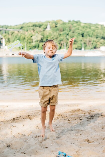 Glücklicher Junge, der am sandigen Ufer springt