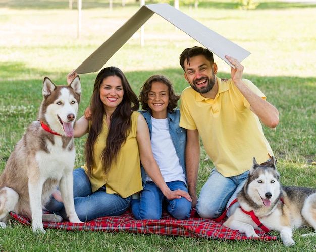 Glücklicher Junge, der im Park mit Hunden und Eltern aufwirft