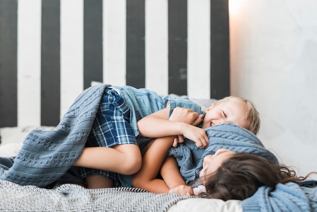 Glücklicher Junge und Mädchen, die auf Bett spielen