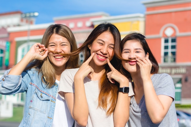 Glücklicher junger Asiatinnengruppenstadtlebensstil, der spielt und sich unterhält