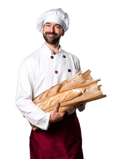 Glücklicher junger Bäcker hält etwas Brot