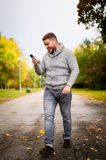 Glücklicher junger Mann, der durch den Park geht