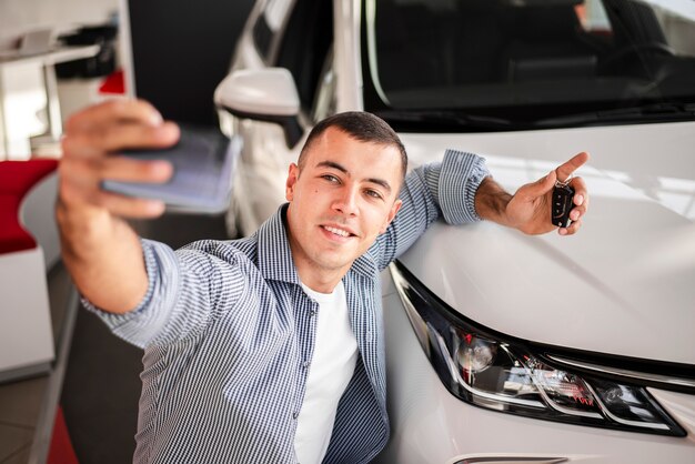 Glücklicher junger Mann, der ein Foto mit dem Auto macht