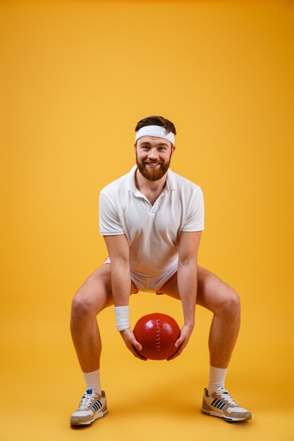 Kostenloses Foto glücklicher junger sportler machen sportübungen, die ball halten.