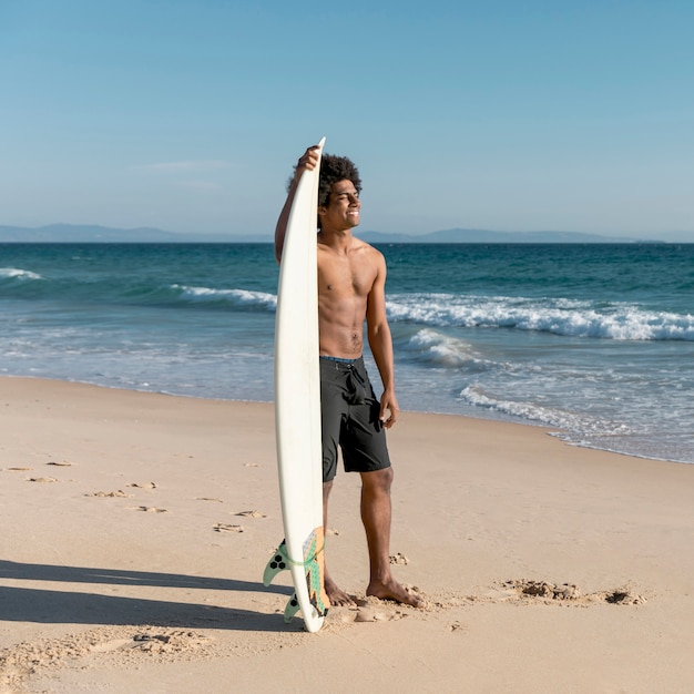 Glücklicher junger Surfer, der blaues Meer betrachtet