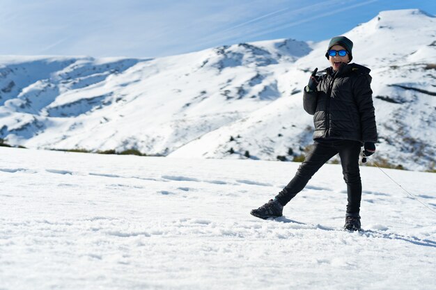 Glücklicher kaukasischer Junge, der warme Kleidung auf dem schneebedeckten Berg im Winter trägt