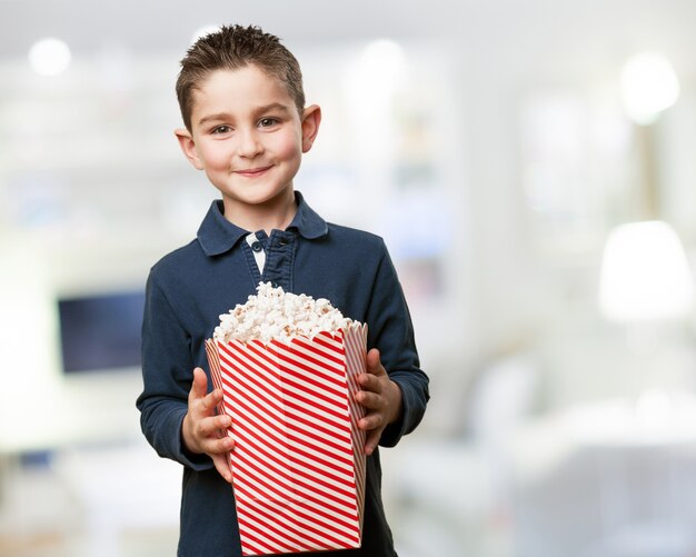 Glücklicher kleiner Junge, der ein Popcorn-Eimer halten