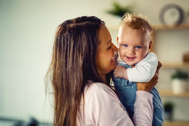 Glücklicher kleiner Junge, der sich zu Hause mit seiner Mutter amüsiert und in die Kamera schaut