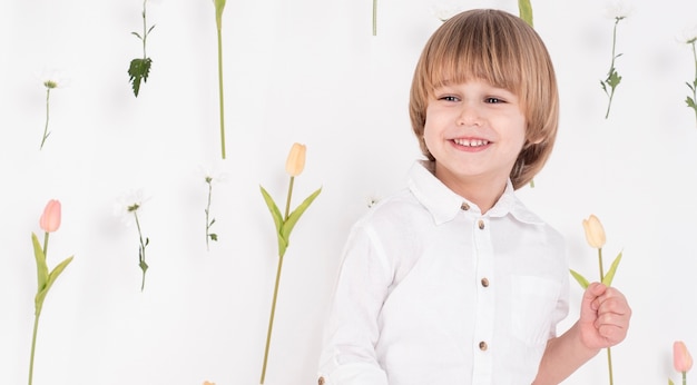 Kostenloses Foto glücklicher kleiner junge, der tulpe hält
