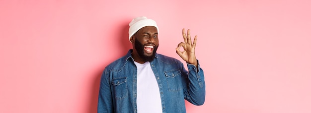 Kostenloses Foto glücklicher lächelnder afrikanisch-amerikanischer mann, der ein okay-zeichen zeigt, genehmigt und lobt ein gutes angebot, das über einer nadel steht