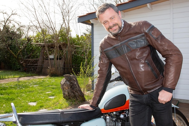 Glücklicher lächelnder biker des gutaussehenden mannes mit vintage-neo-retro-motorrad